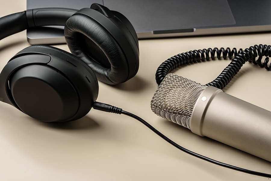 Condenser microphone and overear headphones set down on a desk